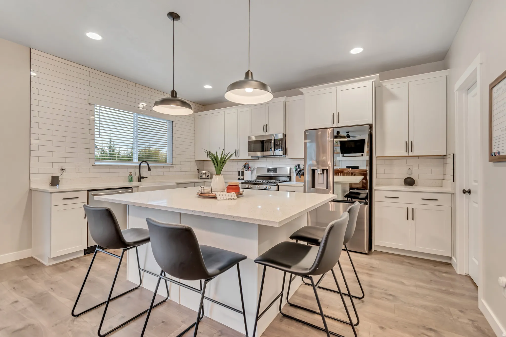 Kitchen featuring stainless steel appliances, white cabinets, light wood-style flooring, a kitchen breakfast bar, and a center island