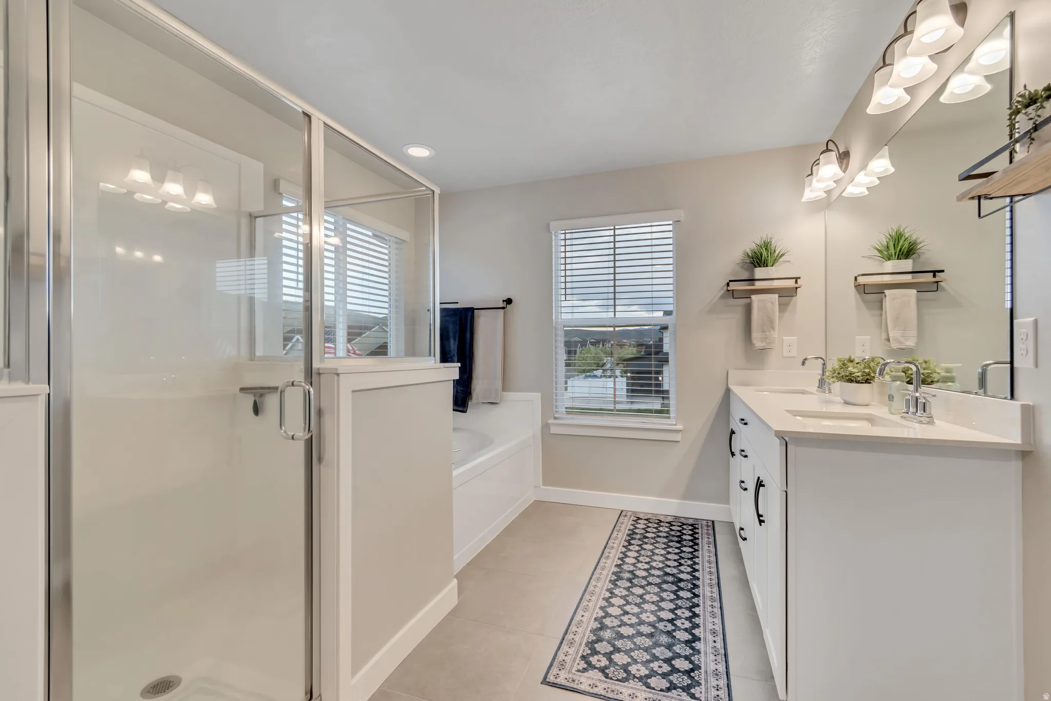 Primary bathroom featuring double vanity, a bath, separate shower, light tile patterned flooring, and recessed lighting