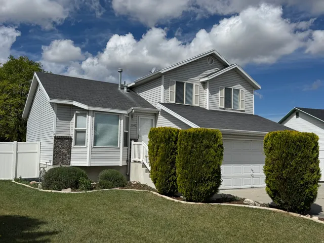 Traditional home featuring roof with shingles, a garage, and concrete driveway