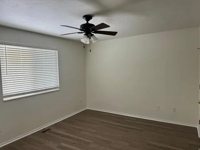 Spare room with dark wood finished floors, a ceiling fan, and a textured ceiling