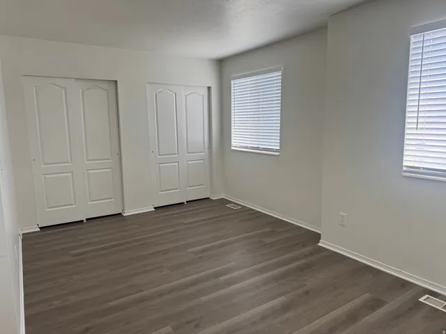 Unfurnished bedroom with multiple closets and dark wood-type flooring