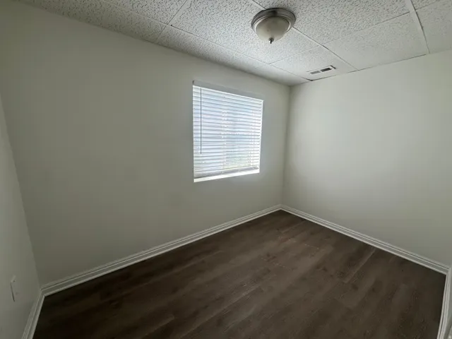 Empty room featuring dark wood-style floors and a paneled ceiling