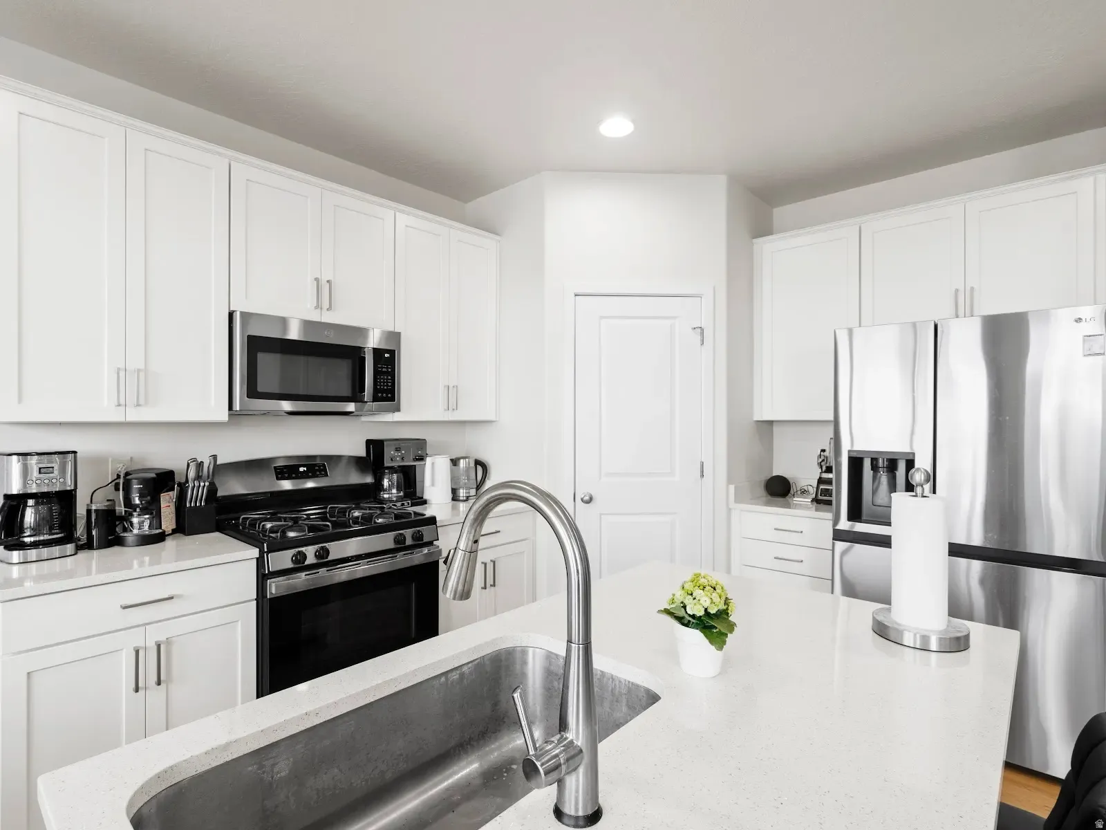 Kitchen featuring stainless steel appliances, white cabinetry, recessed lighting, and light stone counters