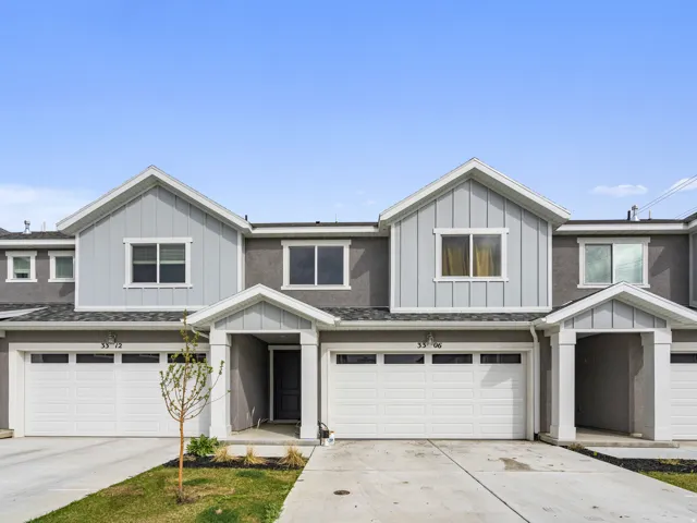View of front of property featuring board and batten siding, an attached garage, and driveway