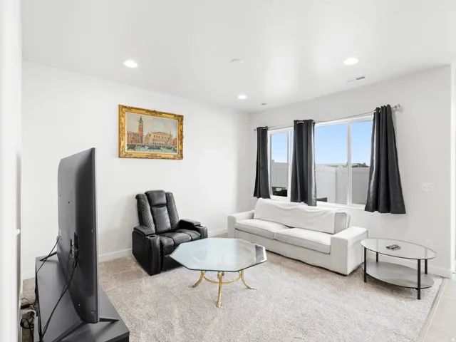 Carpeted living area with recessed lighting and baseboards