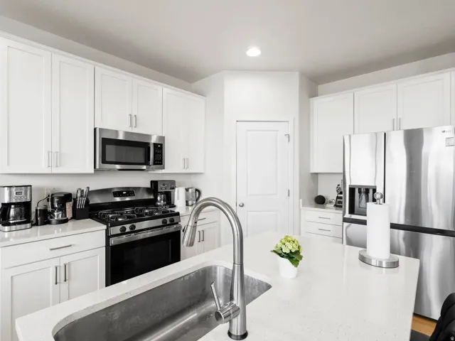 Kitchen featuring stainless steel appliances, white cabinetry, recessed lighting, and light stone counters