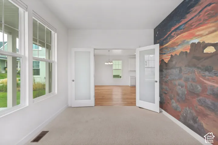 Room featuring multiple windows, a custom wall mural, and light-colored carpeting
