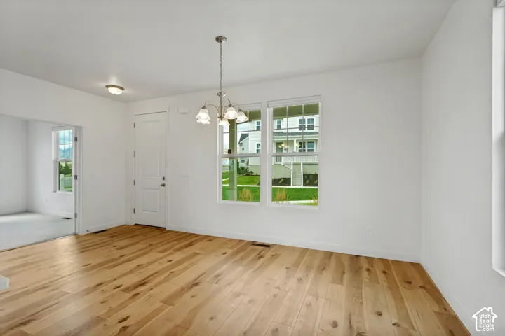 Wood-finish flooring, white walls, and a multi-pane window with a bronze chandelier