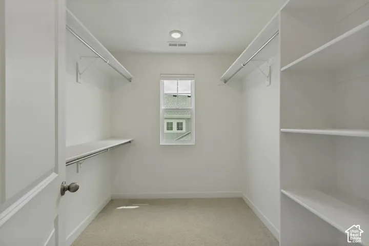 Spacious closet featuring wall-mounted shelving, built-in clothing rods, recessed lighting, and a window