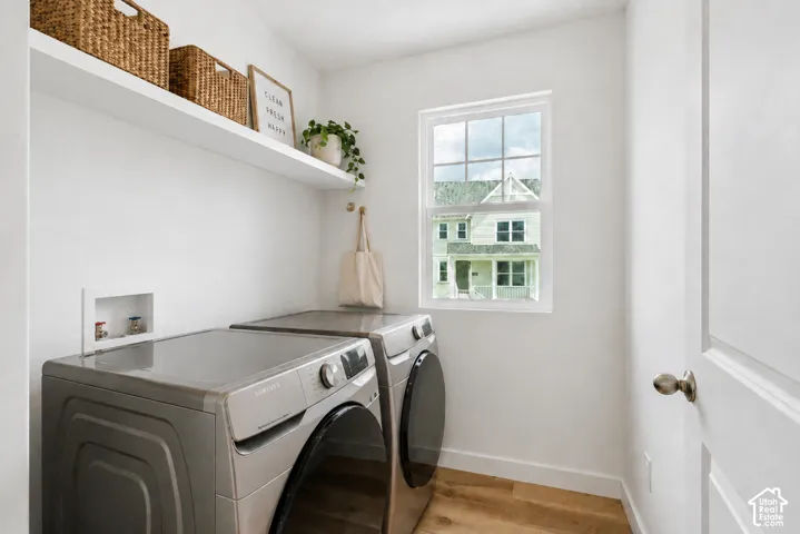 Integrated laundry space featuring a white floating shelf, single window, and wood-finish flooring, WASHER & DRYER INCLUDED, AI staged