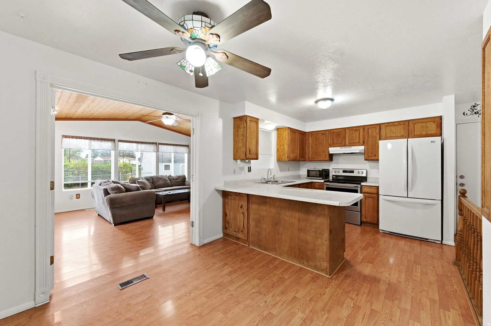 Kitchen with light countertops, freestanding refrigerator, wood finish cabinets, electric range, and open floor plan