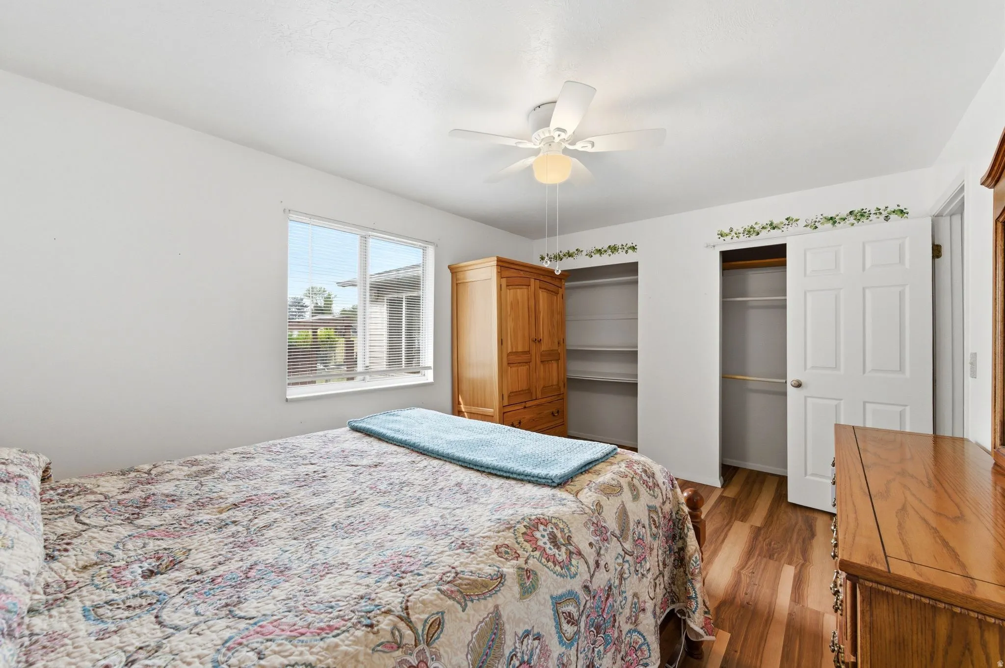 Bedroom with dark wood-style flooring, a ceiling fan, and two closets