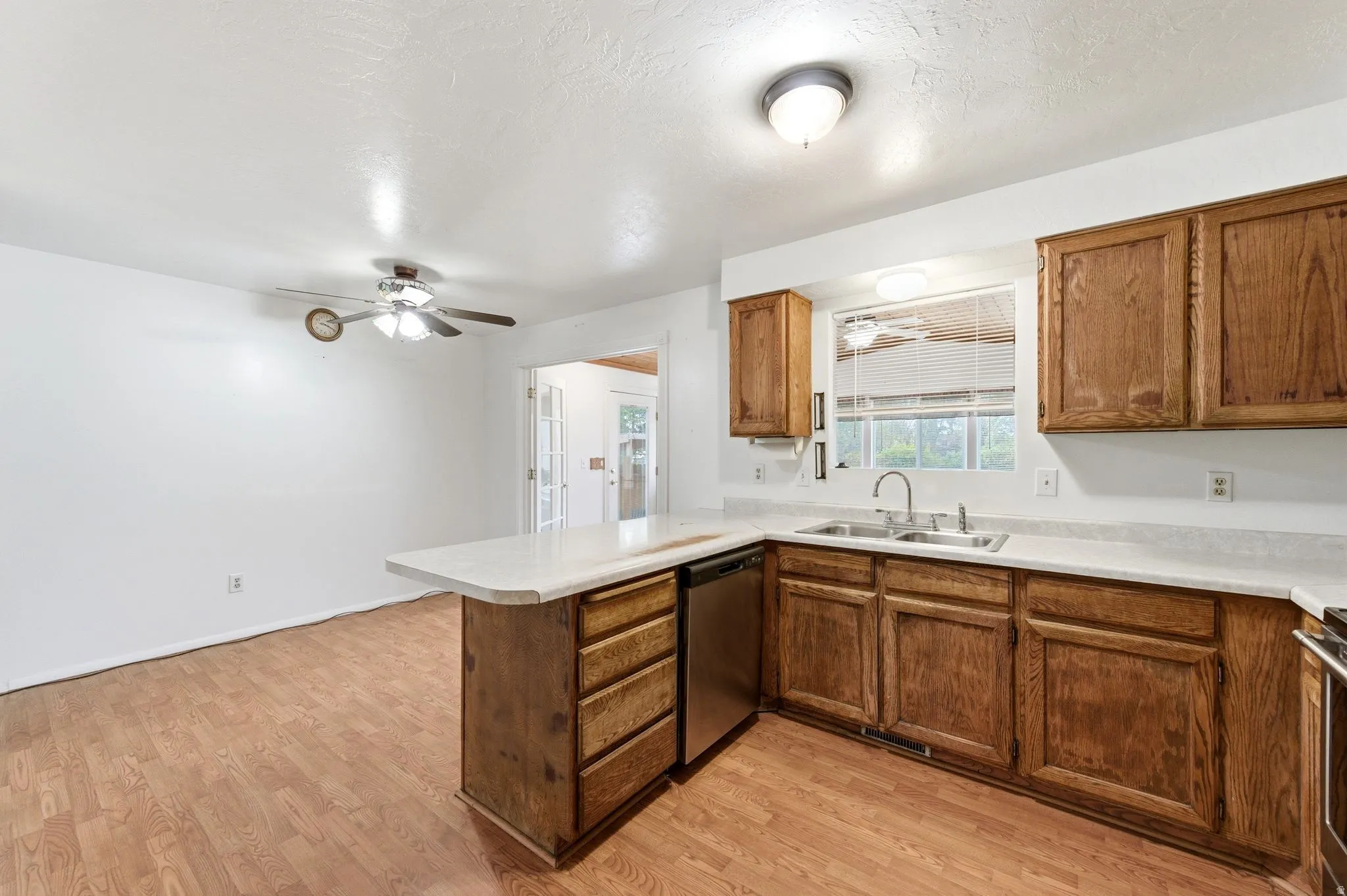 Kitchen with a peninsula, light countertops, wood finish cabinetry, light wood finished floors, and a textured ceiling