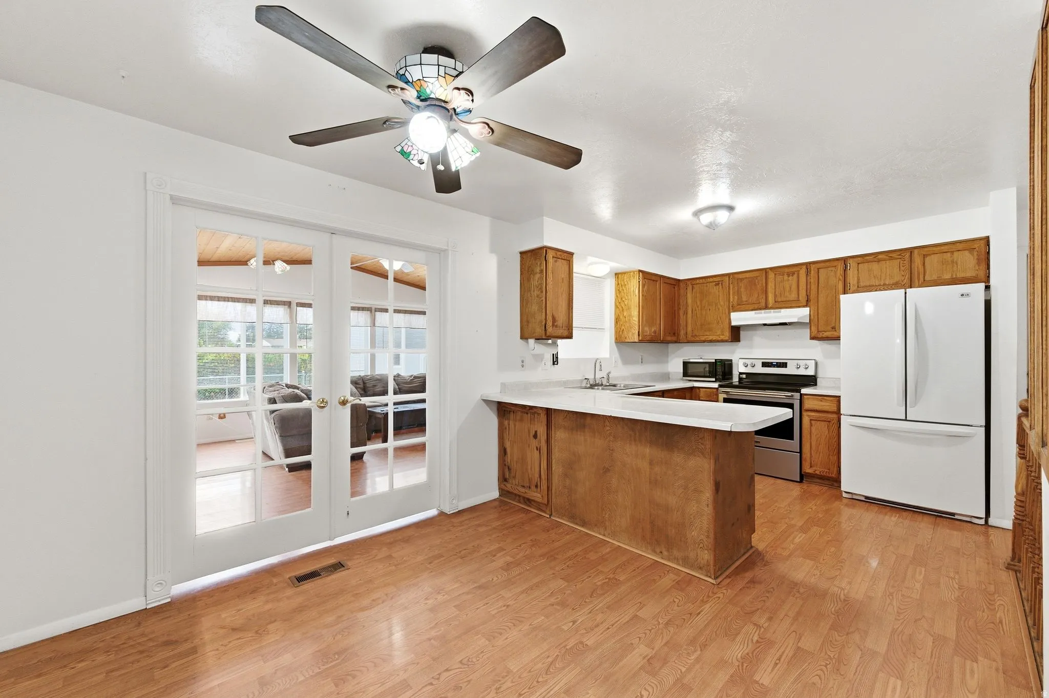 Kitchen with wood finish cabinets, light countertops, freestanding refrigerator, electric range, and french doors