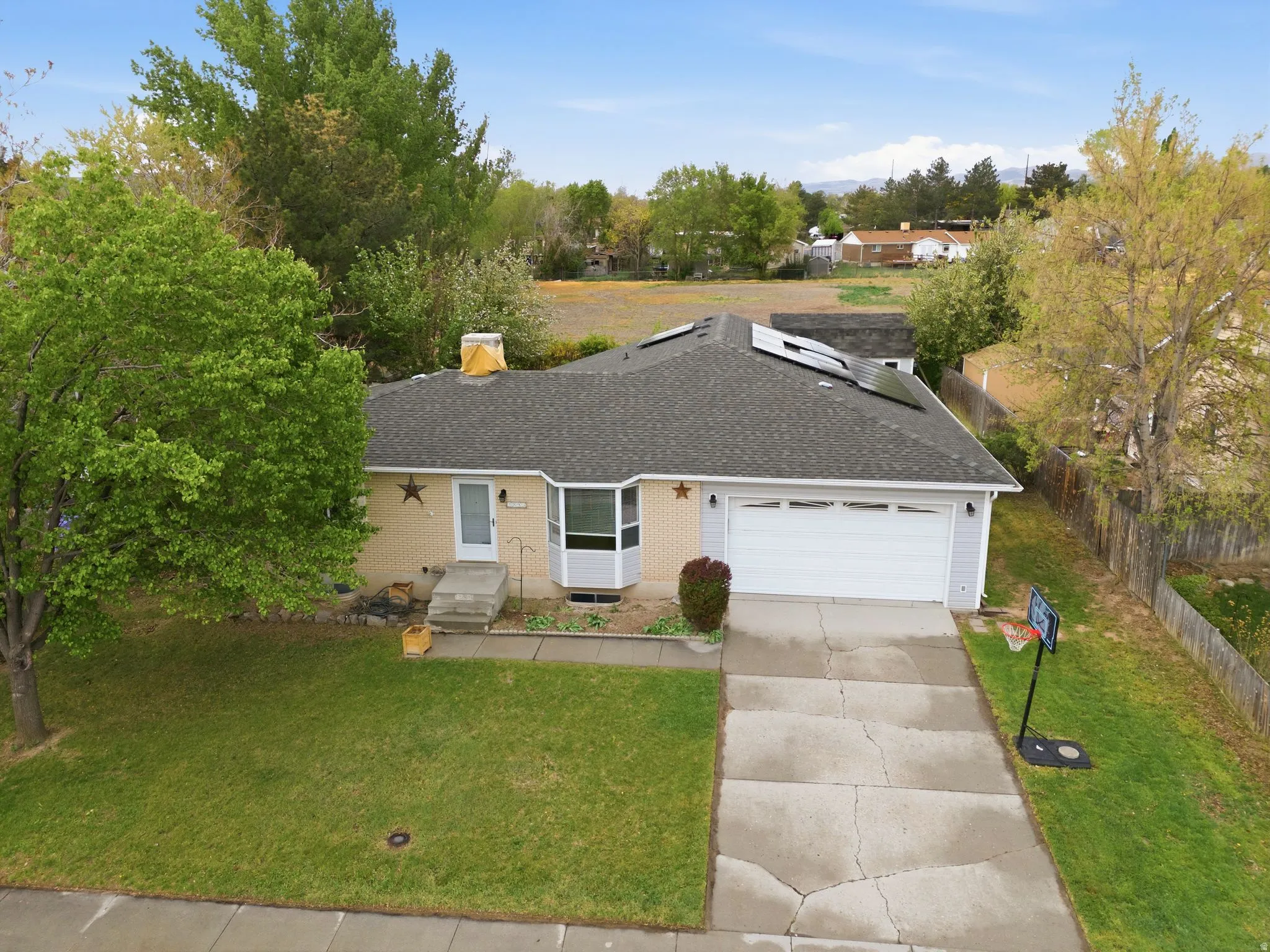 View of front of house featuring driveway, a garage, roof with shingles, brick siding, and solar panels