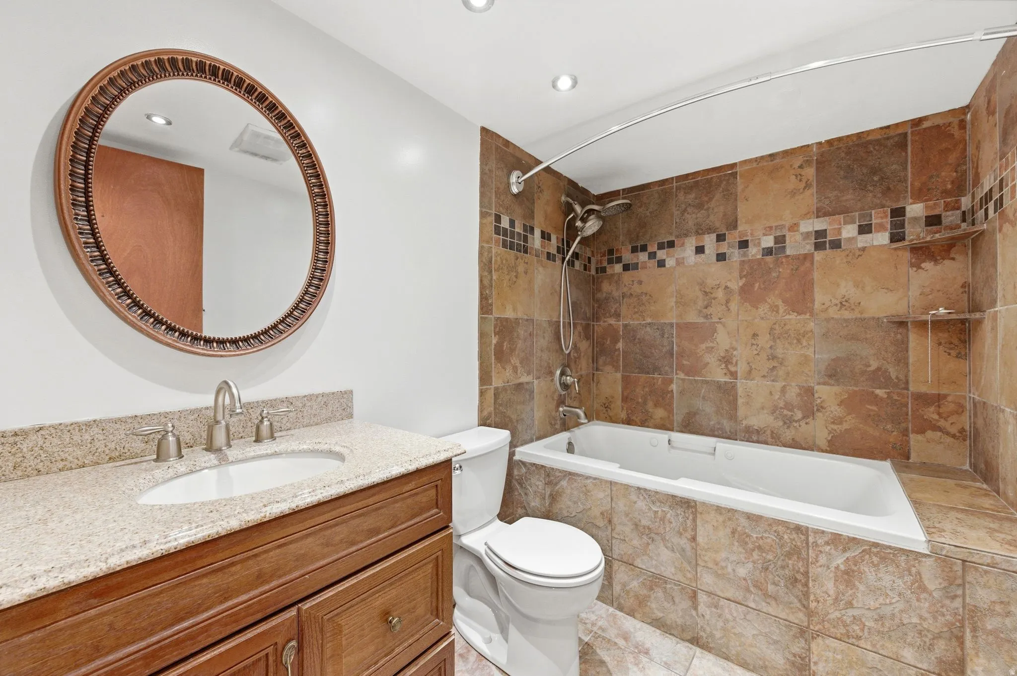 Full bathroom with vanity, tiled shower / bath combo, and recessed lighting