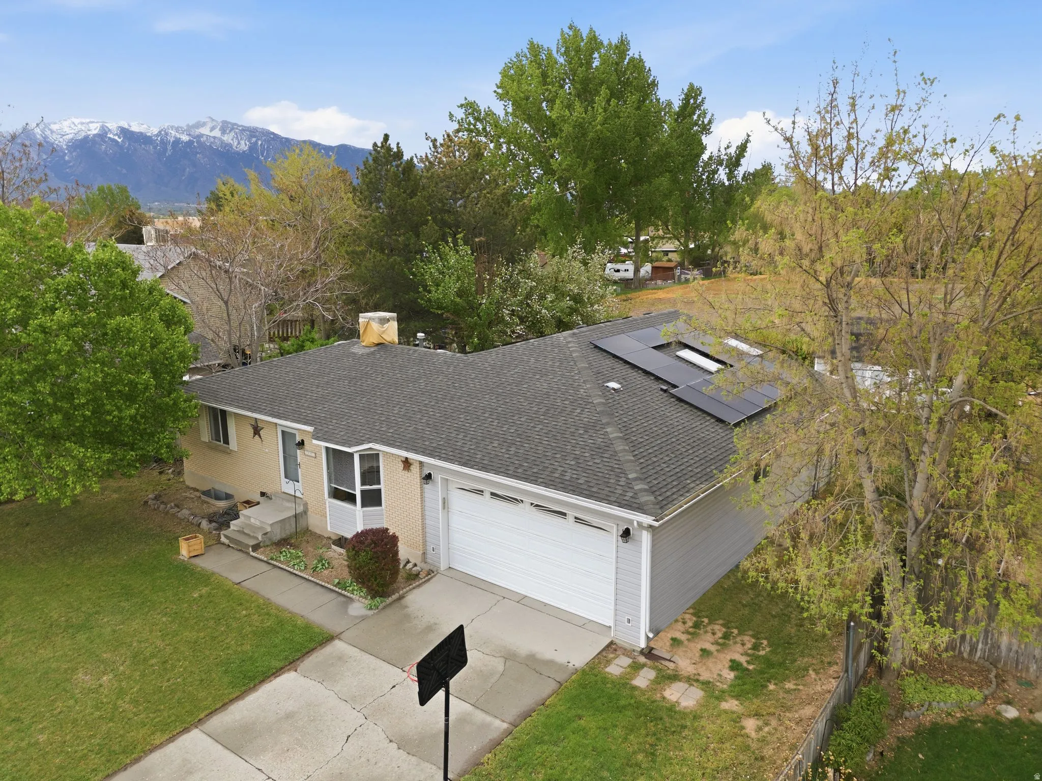 View of front of property with roof with shingles, solar panels, an attached garage, and concrete driveway