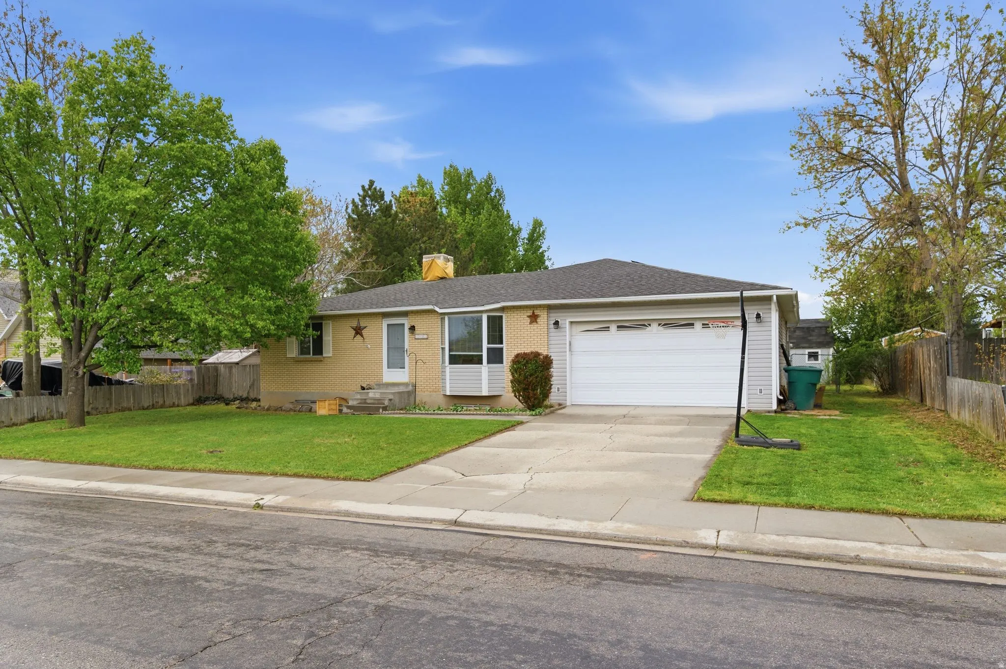 Single story home featuring an attached garage, driveway, a chimney, and brick siding