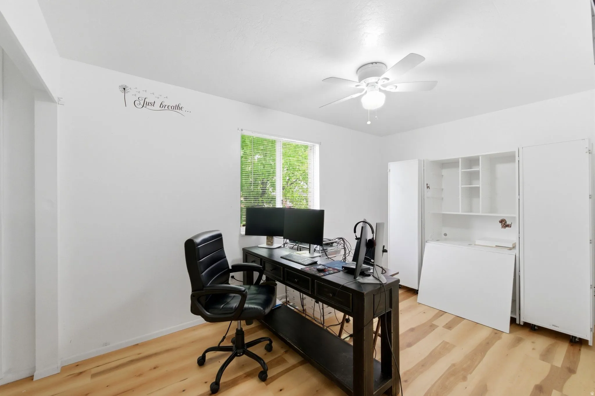 Office space with light wood-style floors and ceiling fan