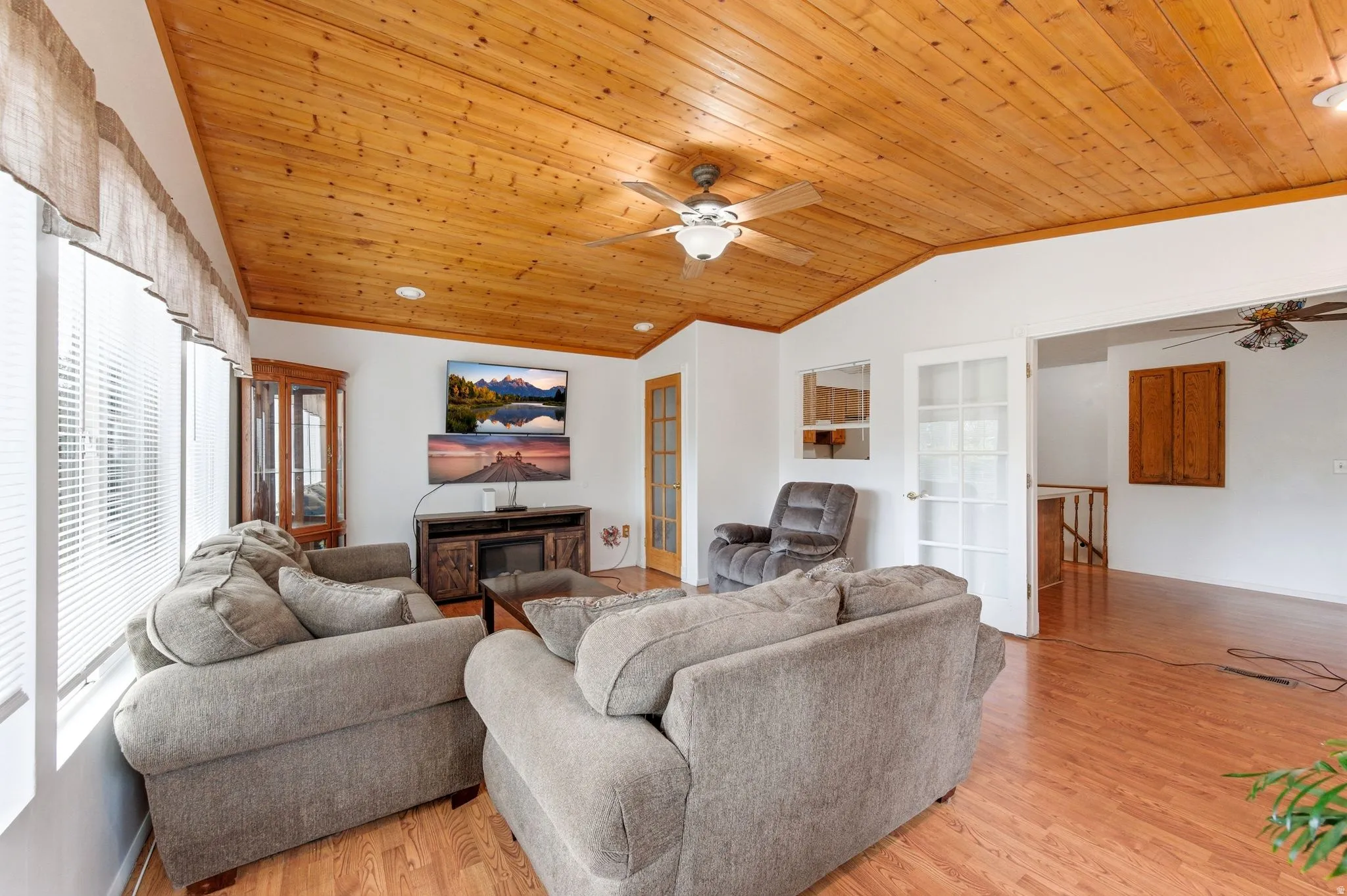 Living area featuring ceiling fan, light wood finished floors, a vaulted wooden ceiling, ornamental molding, and french doors