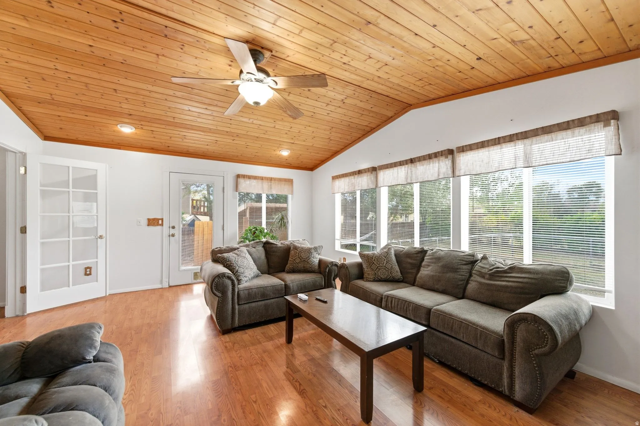Living room with a vaulted wood ceiling, ceiling fan, light wood finished floors, and crown molding