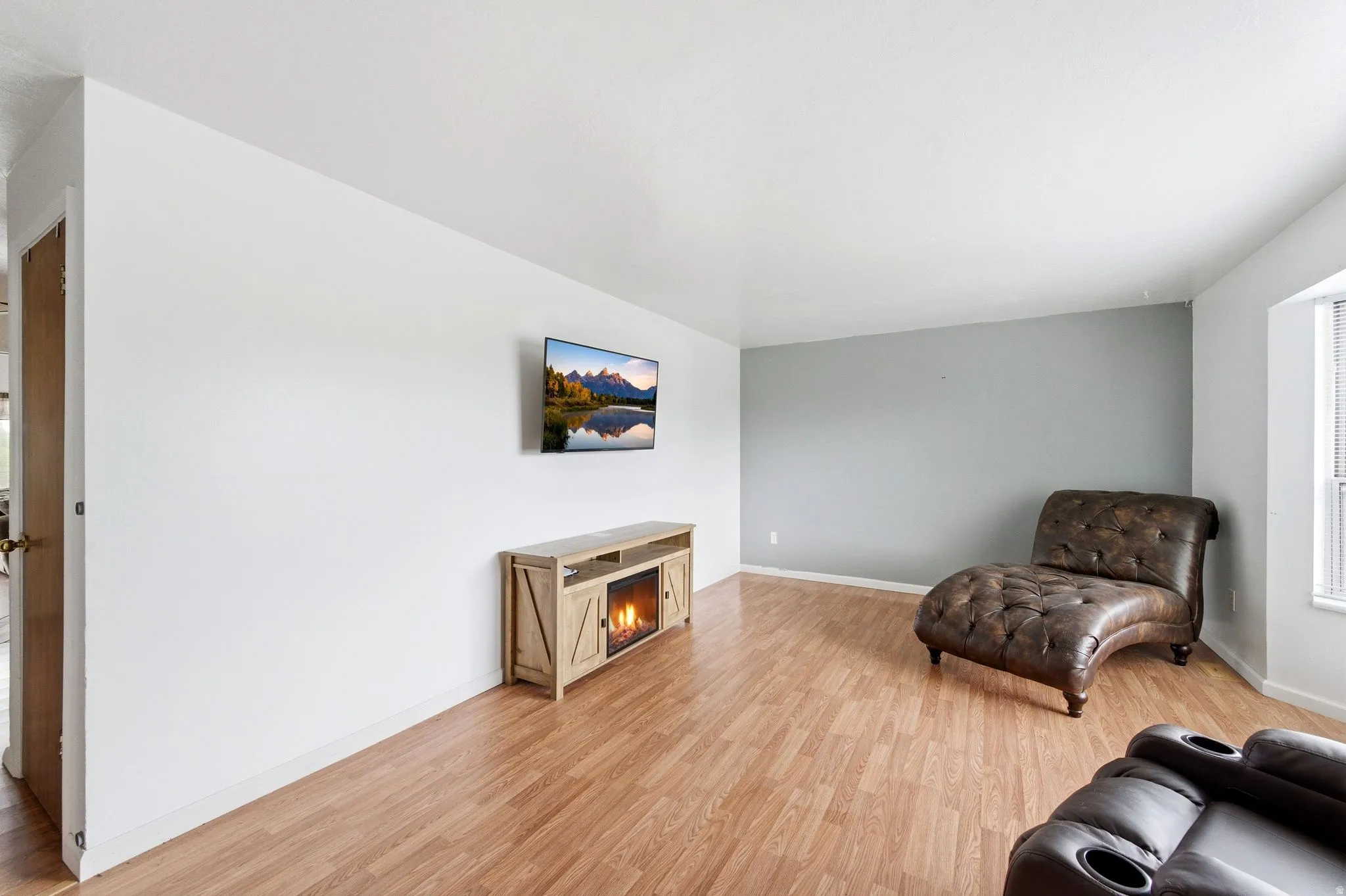 Sitting room featuring light wood finished floors and a warm lit fireplace