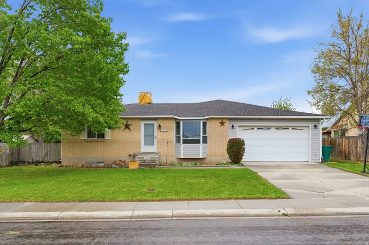 Single story home featuring brick siding, concrete driveway, an attached garage, a shingled roof, and a chimney