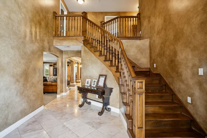 Stairs with a high ceiling, arched walkways, a textured wall, and tile patterned flooring