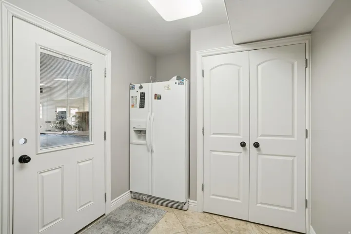 Interior space with white refrigerator with ice dispenser and light tile patterned floors