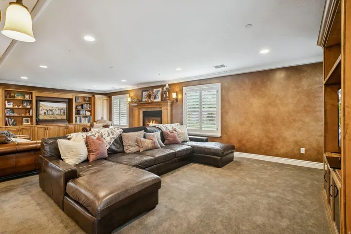 Carpeted living room with plenty of natural light, a lit fireplace, ornamental molding, and recessed lighting