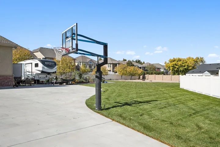View of basketball court featuring a fenced backyard, a residential view, and basketball hoop