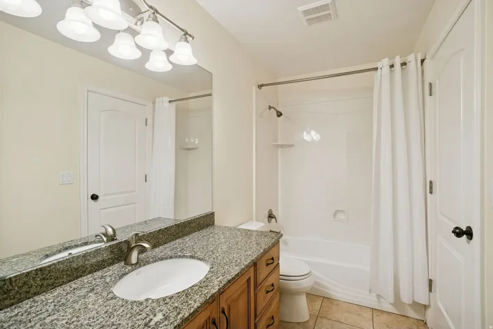 Full bath with light tile patterned floors, vanity, and shower / bath combo