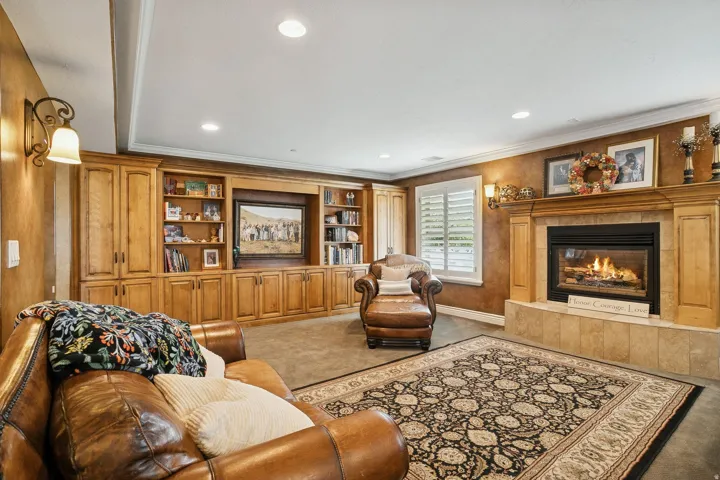 Carpeted living area with a tiled fireplace, recessed lighting, ornamental molding, and built in features