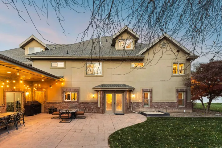 Rear view of house featuring brick siding, a patio, stucco siding, a shingled roof, and a lawn