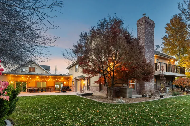 Back of house featuring a lawn, a chimney, a patio, and brick siding