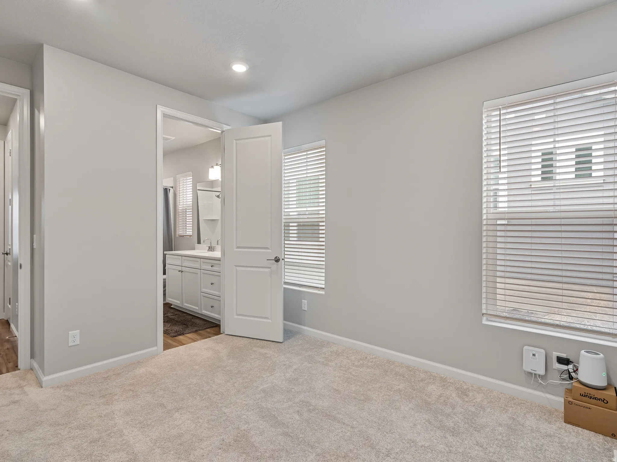 Unfurnished bedroom with dark colored carpet, ensuite bathroom, and recessed lighting