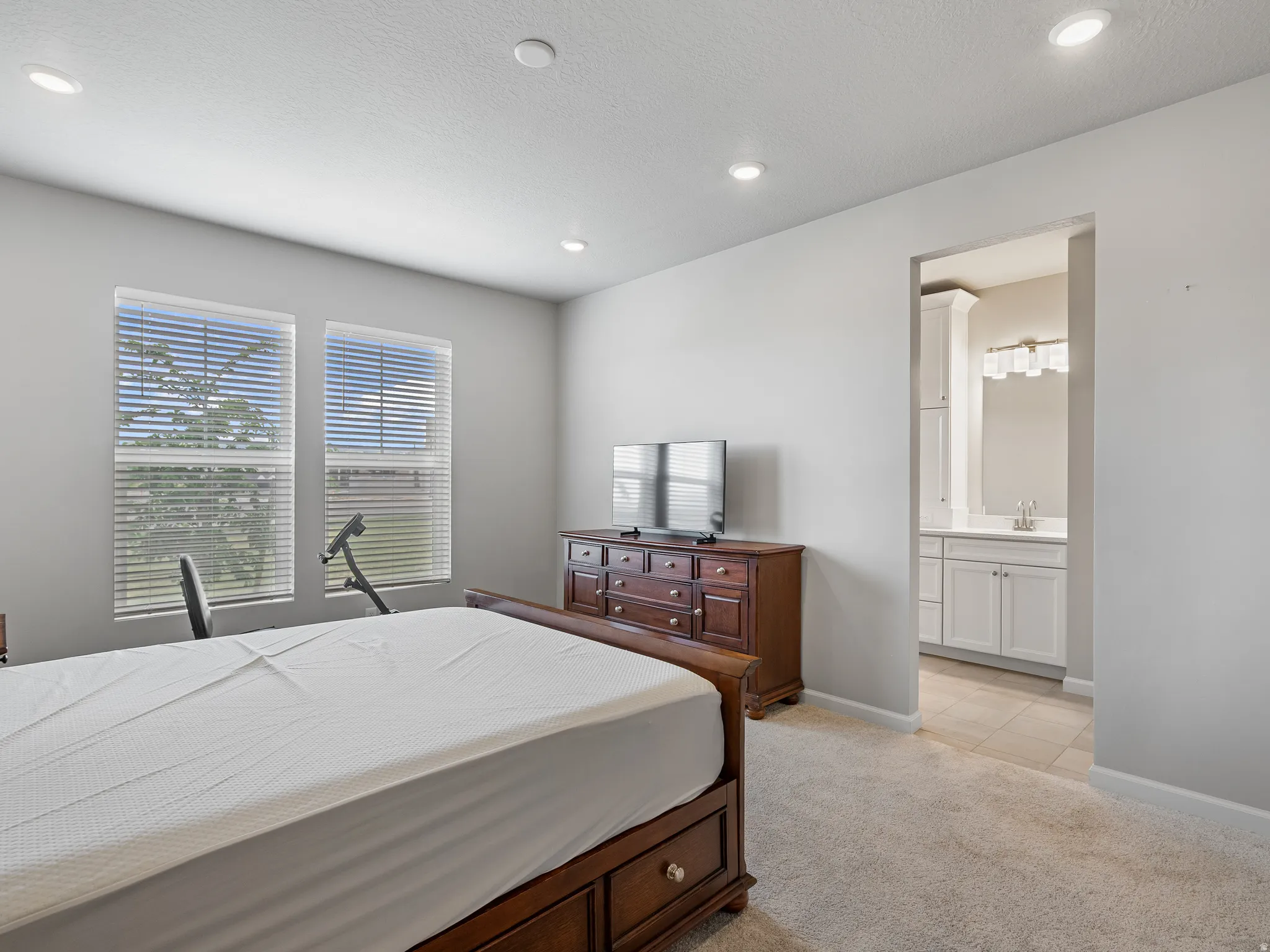 Bedroom featuring light carpet, ensuite bathroom, and recessed lighting
