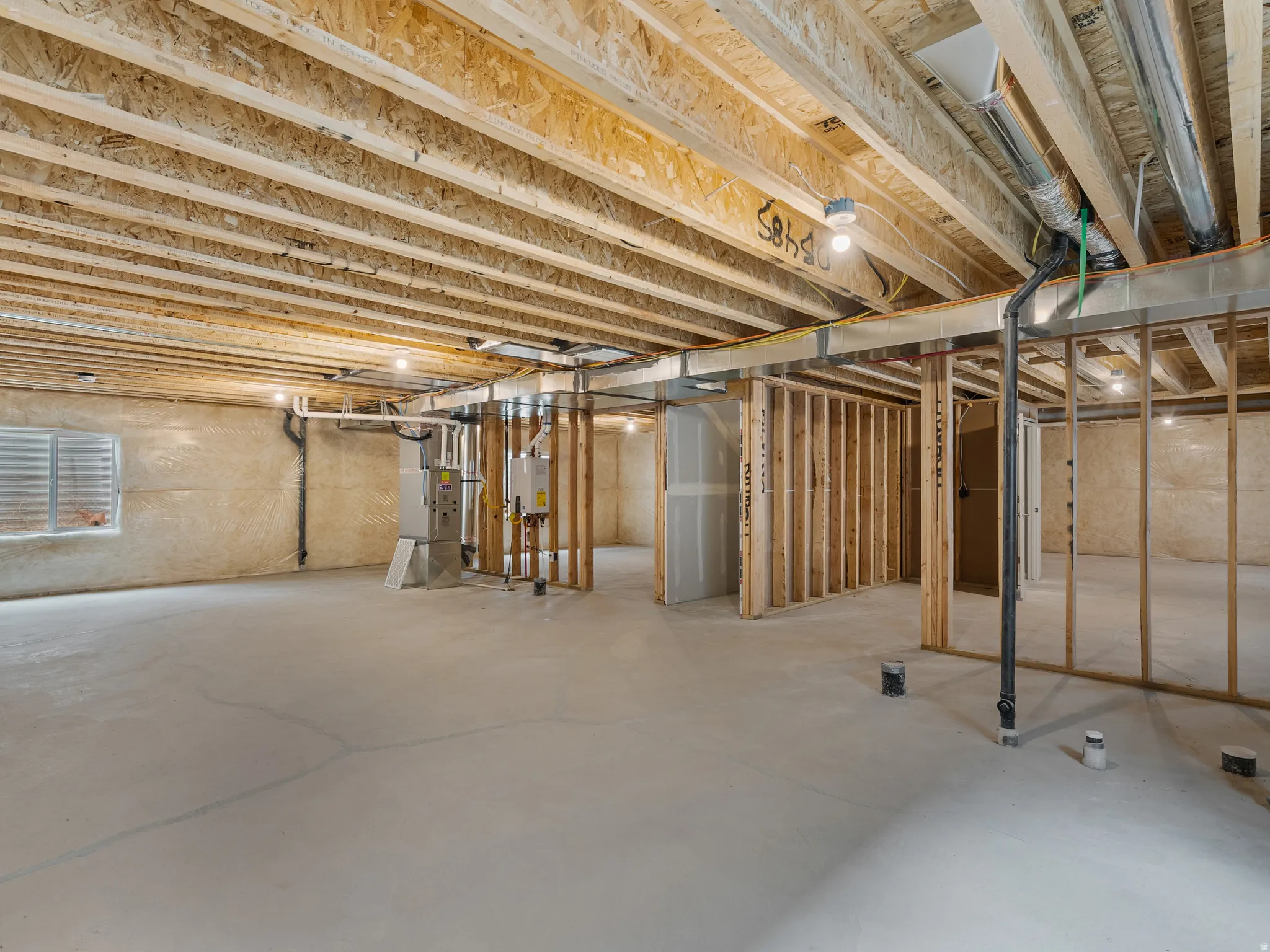 Unfinished basement featuring heating unit and tankless water heater