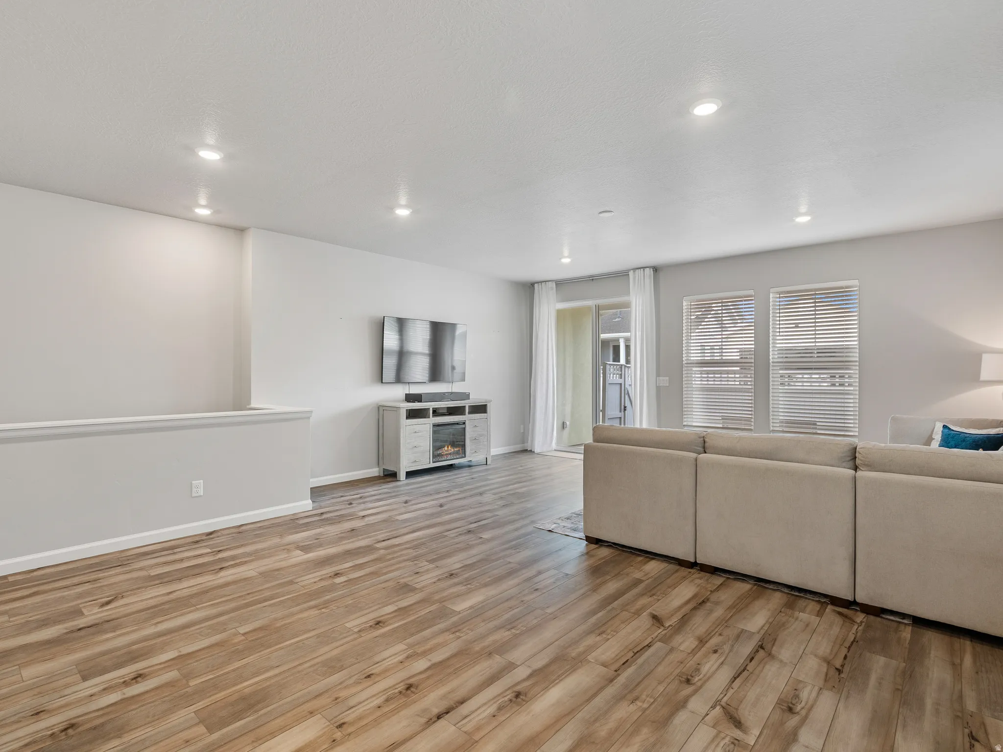 Living room with light wood-style flooring, recessed lighting, and a glass covered fireplace