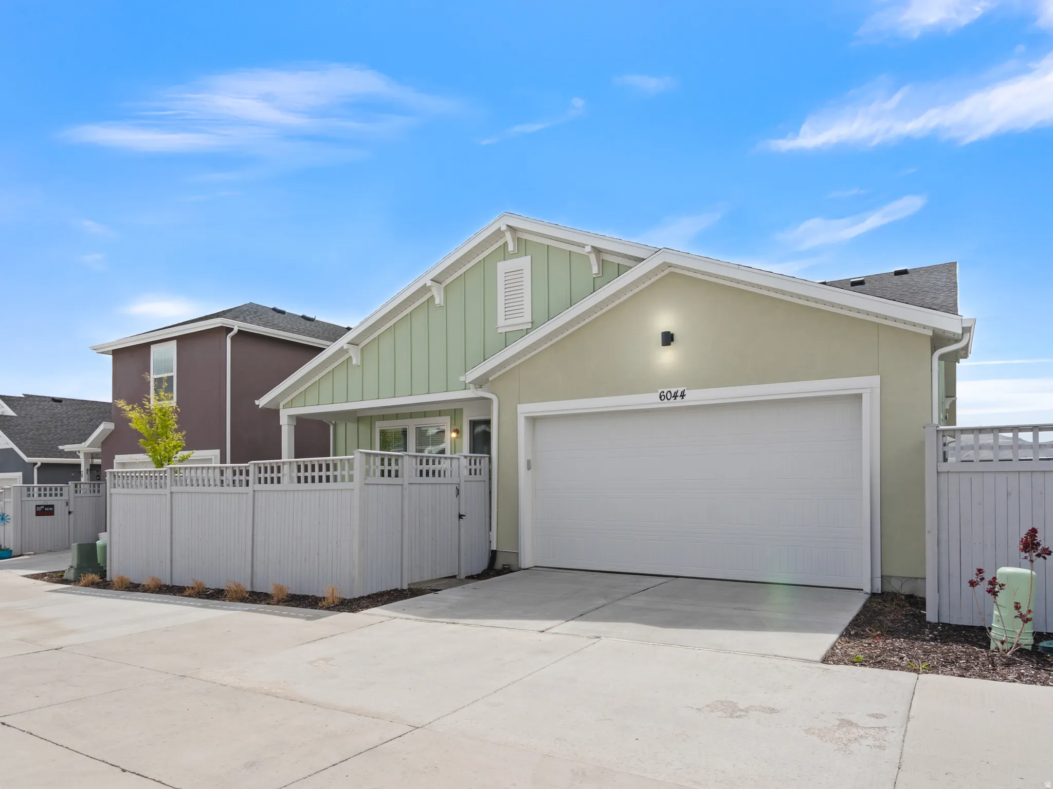 View of front of house featuring driveway, board and batten siding, an attached garage, and a gate