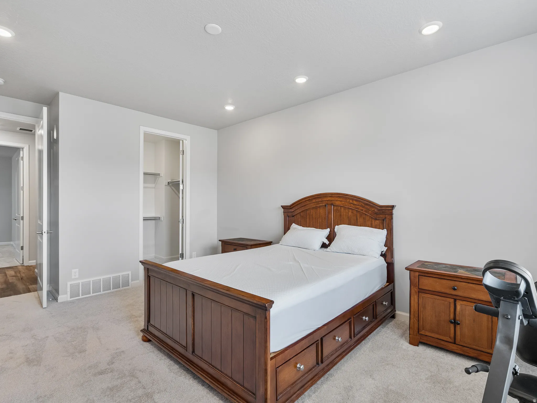 Bedroom featuring light carpet, a walk in closet, and recessed lighting