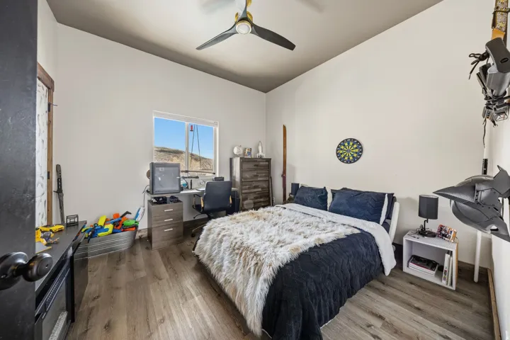 Bedroom with wood finished floors, ceiling fan, and vaulted ceiling