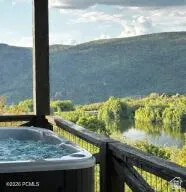 Balcony with a water view and a hot tub