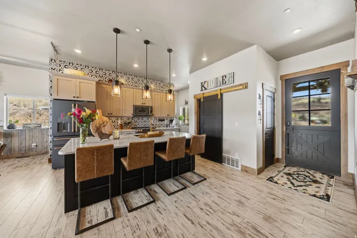 Kitchen with plenty of natural light, a kitchen island with sink, stainless steel appliances, and light stone counters