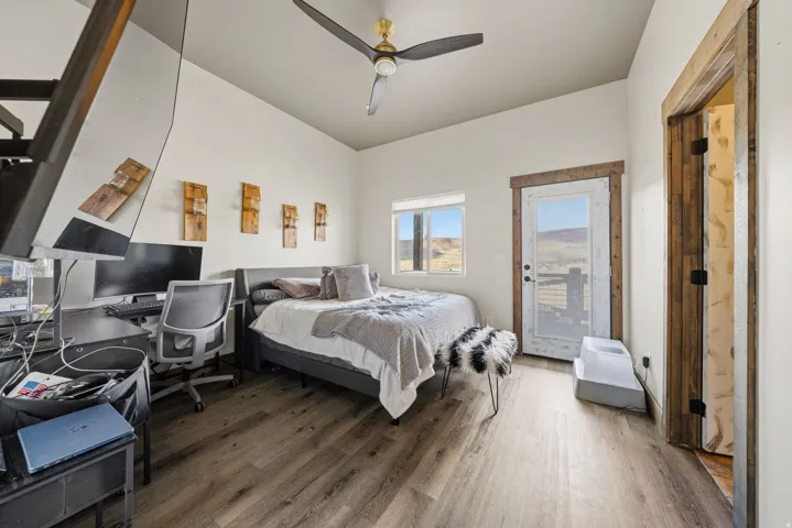 Bedroom featuring access to exterior, wood finished floors, a desk, and a ceiling fan