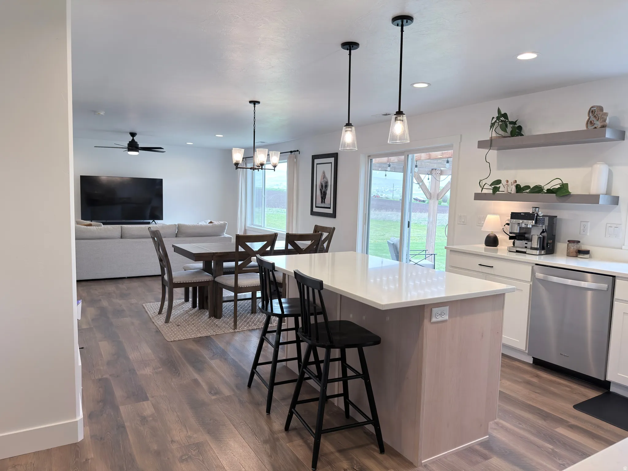 Two tone kitchen with a center island, dishwasher, open shelves, a kitchen bar, and open floor plan