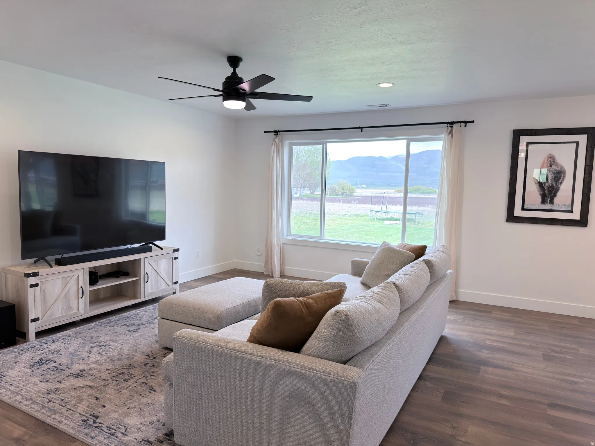 Living room featuring dark wood-style flooring, ceiling fan, and a mountain view