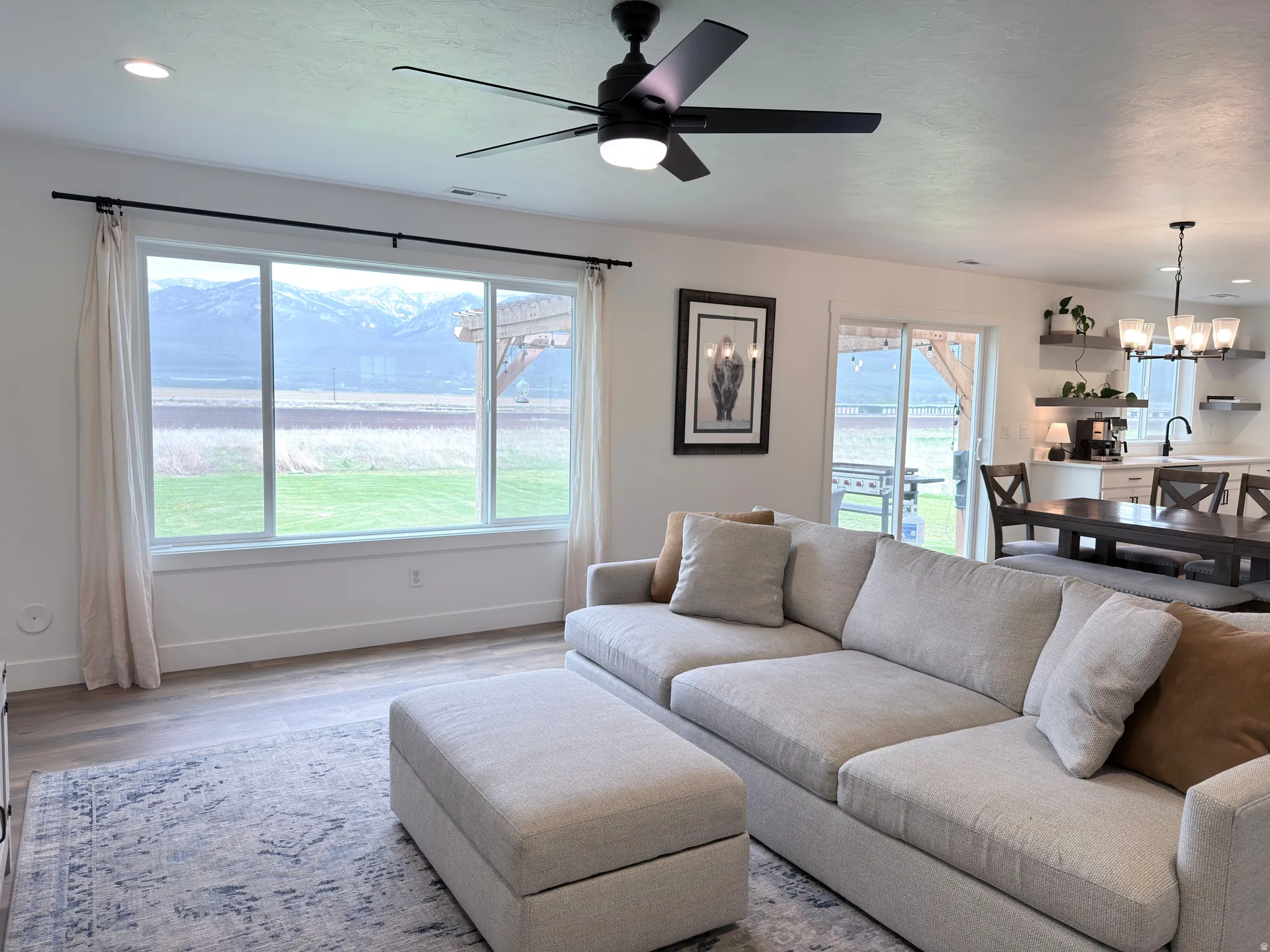 Living room featuring a ceiling fan, wood finished floors, and suspended lighting