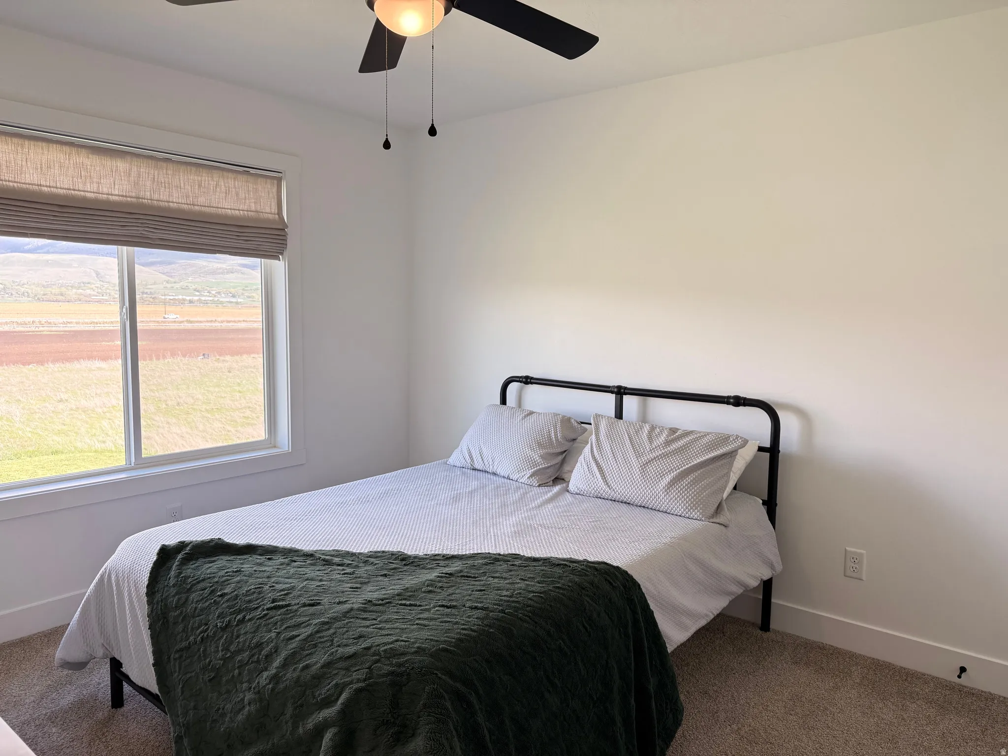 Carpeted bedroom featuring ceiling fan and a mountain view