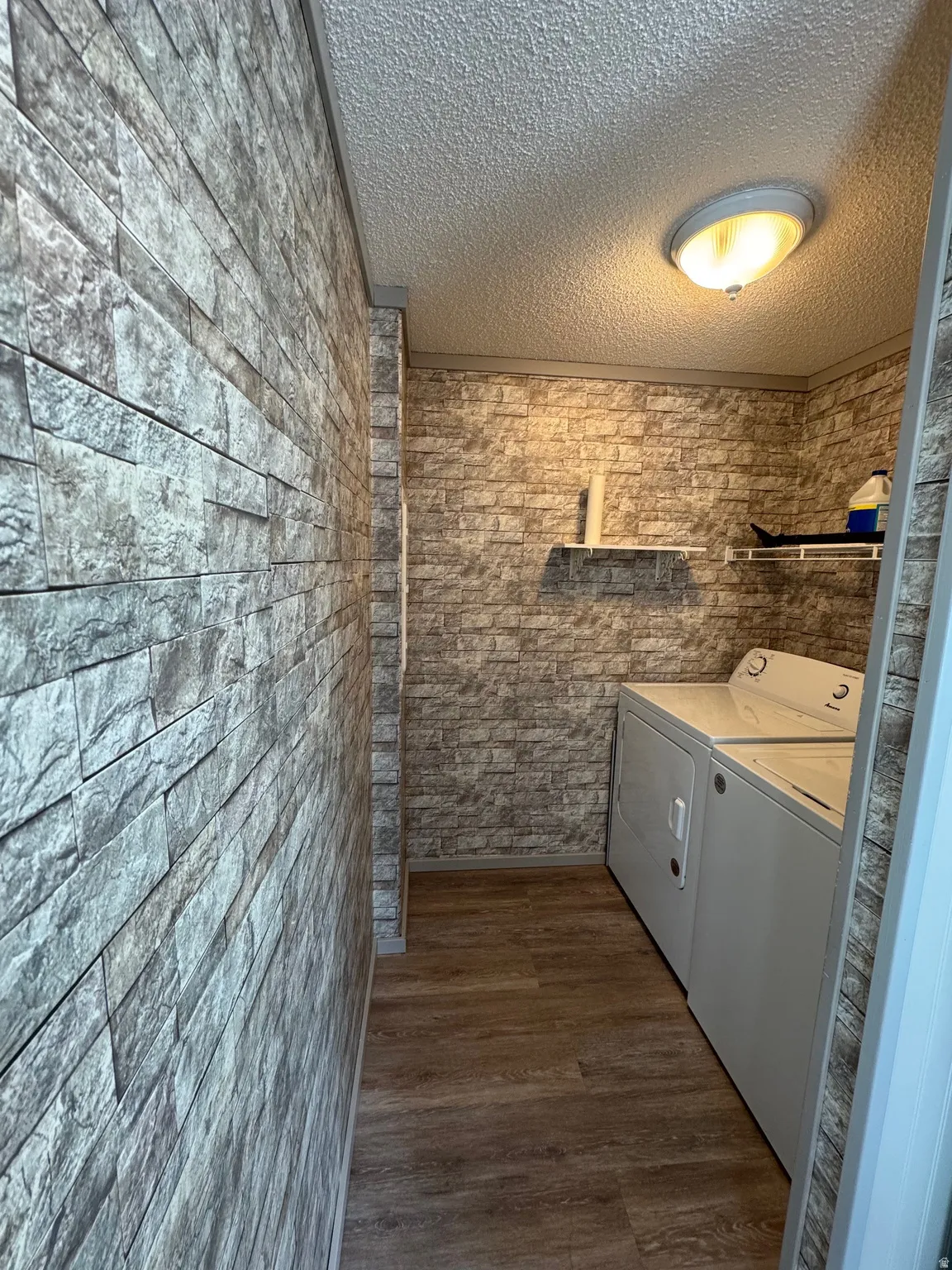 Laundry room featuring a textured ceiling, dark wood-style floors, and washer and dryer